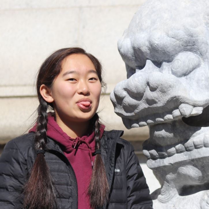 Serena sticking her tongue out next to a large stone gargoyle