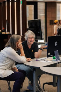 Elizabeth Hodas showing Colleen Coxe how to use Google Gemini Chat.